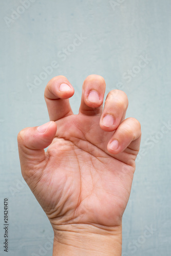 Trigger Finger lock on fingers of woman's front left hand, Suffering from pain, On Blue-grey colour background, Close up & Macro shot, Office syndrome, Health care concept