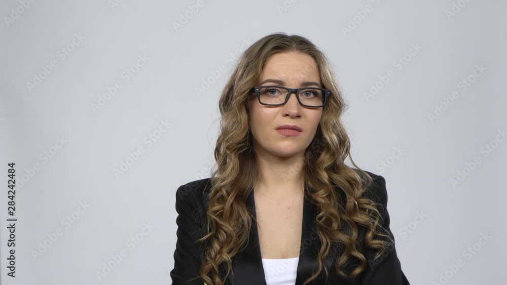 Female disappointed looks in camera and shrugs then waving his head no against grey background Female disappointed looks in camera and shrugs then waving his head no against grey background