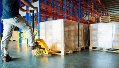 warehouse worker working with hand pallet truck and cargo shipment pallet at distribution warehouse supply chain package boxes on wooden pallet cargo export for transportation.
