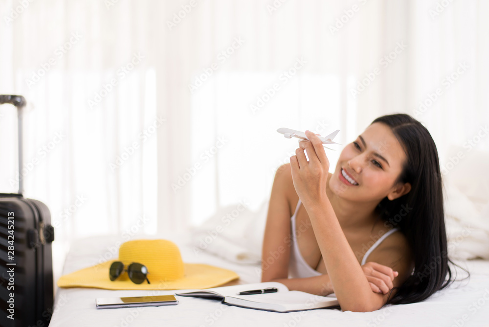 Happy asian woman hands holding airplane model and planning vacation with travel accessories in bedroom Happy asian woman hands holding airplane model and planning vacation with travel accessories in bedroom