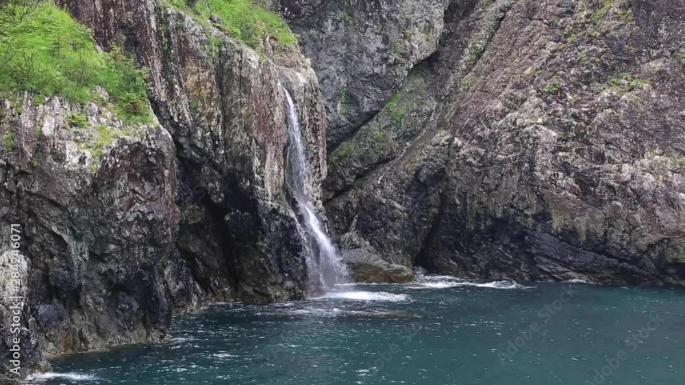 Waterfall on rugged coastline of keno Fjiords National Park Waterfall on rugged coastline of keno Fjiords National Park
