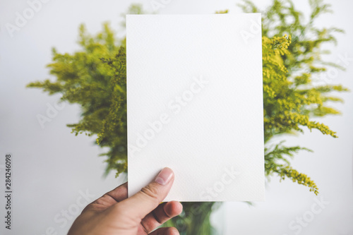 Foto Hands Holding Card With Flowers In The Background. Mock up
