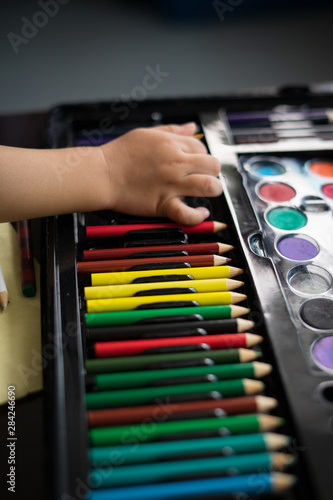 Small hand is trying to take the coloured pencils. Creative kids concept.