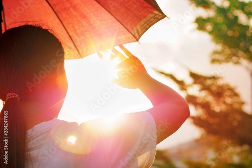 Hot weather can cause dehydration and sunstroke The girl is holding an umbrella and raising her hand. To block the hot sunlight.. (Devices that are not specific to a particular brand)