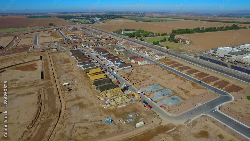 Rotating and pulling aerial shot over a construction site of new home builds with a crane. In the desert of Arizona Rotating and pulling aerial shot over a construction site of new home builds with a crane. In the desert of Arizona