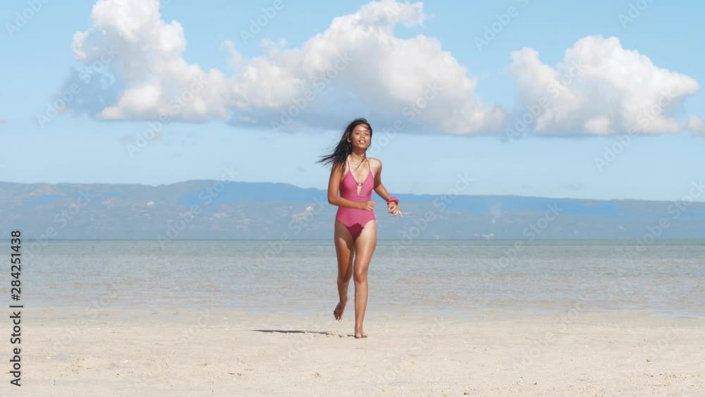 Pretty asian girl jogging in swimsuit on sand ocean tropical island, front view. Pretty asian girl jogging in swimsuit on sand ocean tropical island, front view.
