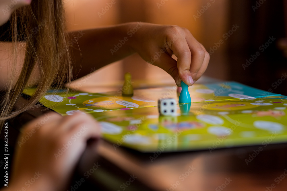 Fototapeta premium Multi-colored game chips with dice on the playing board. Board game.children sit in kindergarten at the table engaged, learn in the nursery,Playing table game.