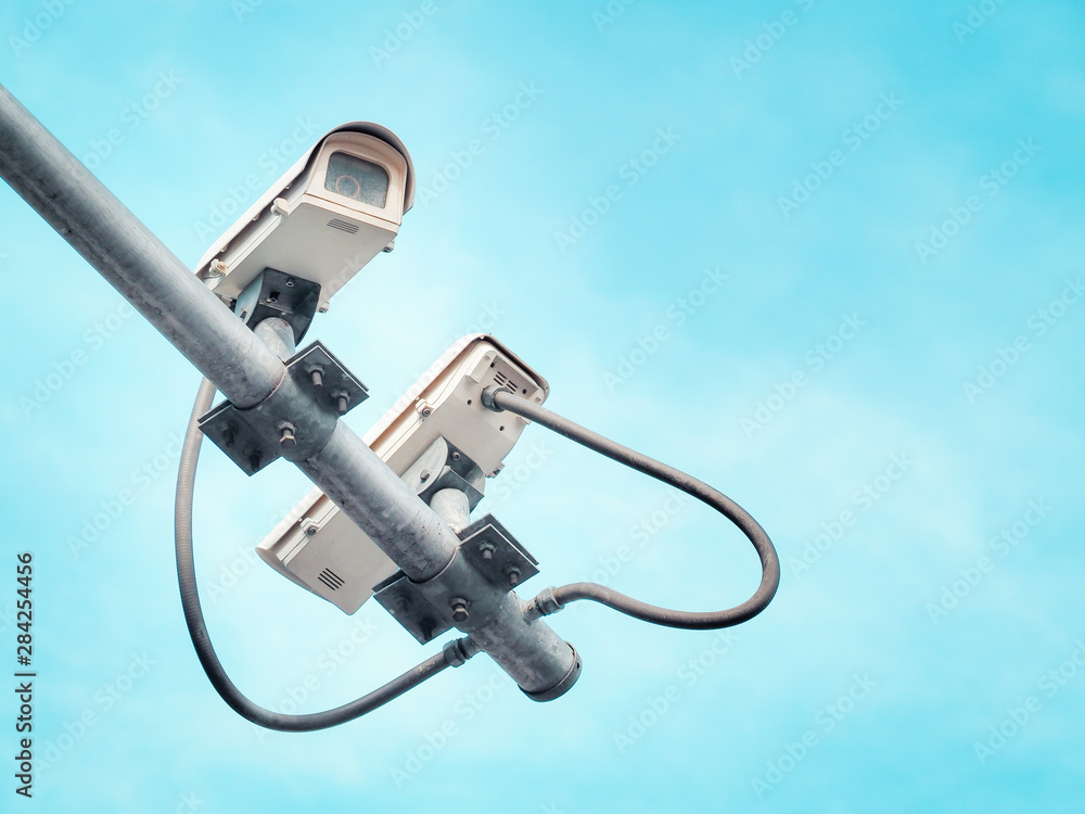 2 CCTV security cameras on a high pole for public protection. Surveillance CCTV in the city against blue sky.