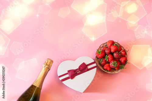 Bottle of champagne, heart shape gft box and fresh strawberry on pink background photo