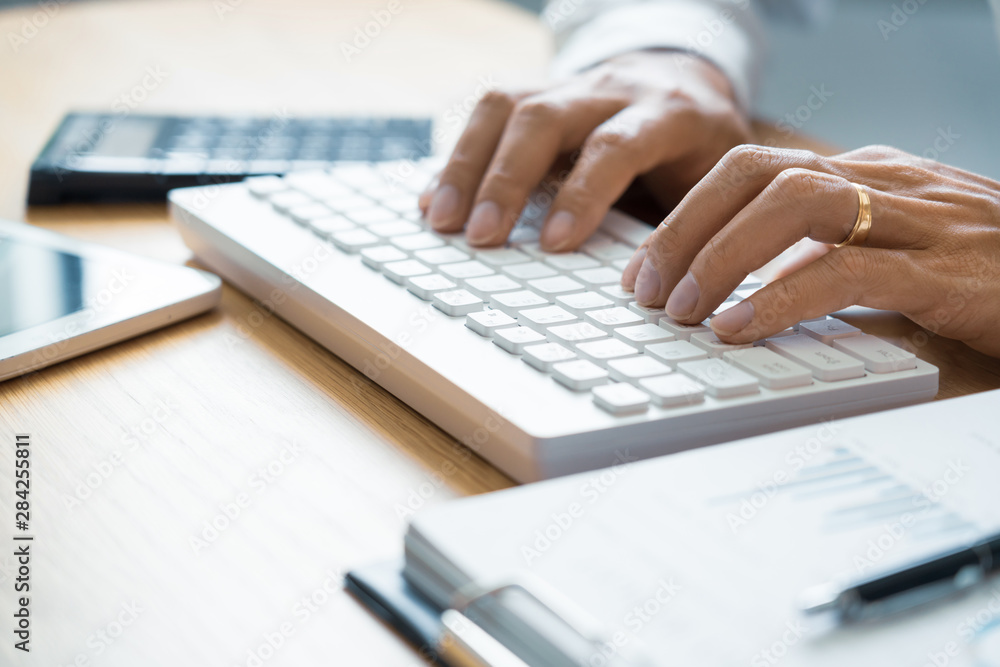 Close-up of male hands typing on keyboard Working On Compute Sitting Table And Office Tools At Workplace, writing emails, communicating online concept. Close-up of male hands typing on keyboard Working On Compute Sitting Table And Office Tools At Workplace, writing emails, communicating online concept.