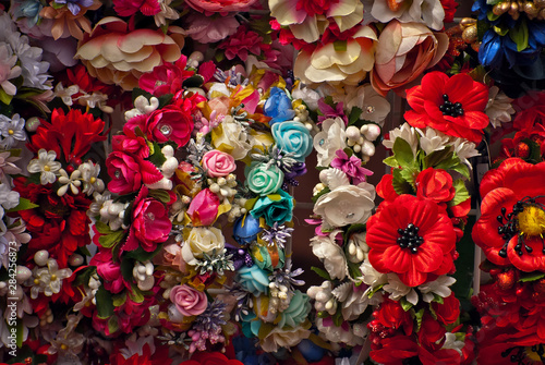 Bouquets of artificial flowers are sold at the fair. Corollas of colored small flowers. Closeup of national decorations and accessories for clothing.