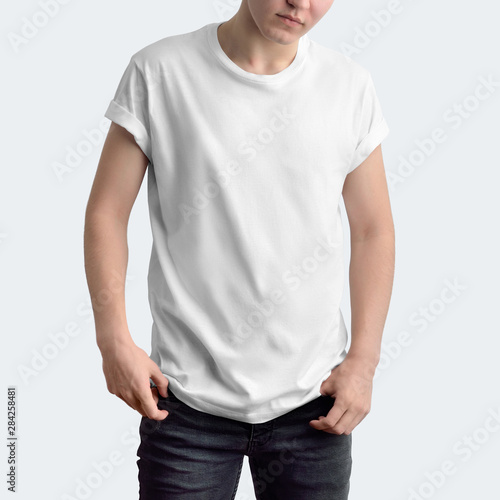 Attractive slim guy in a blank T-shirt and dark jeans on a white studio background.