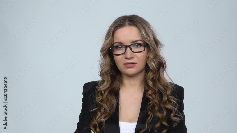 Female disappointed looks in camera and shrugs then waving his head no against grey background, slow motion Female disappointed looks in camera and shrugs then waving his head no against grey background, slow motion