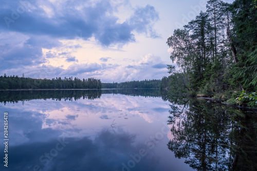 Scenic summer night landscape with mood light and beautiful reflections at lakeside in Finland.
