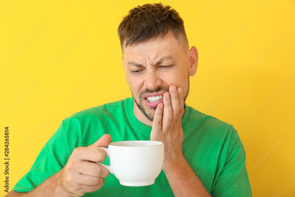Man with sensitive teeth and hot coffee on color background Man with sensitive teeth and hot coffee on color background