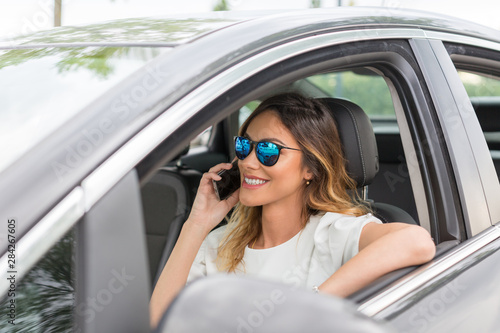 Attractive young woman talking on the mobile cell phone in her car