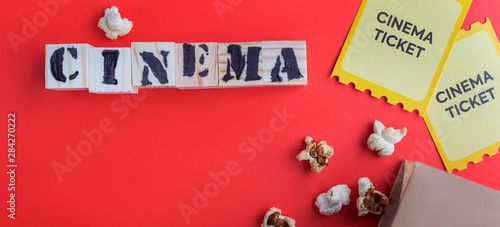 craft bag with popcorn two yellow cinema tickets puzzle wooden cubes with text cinema red background