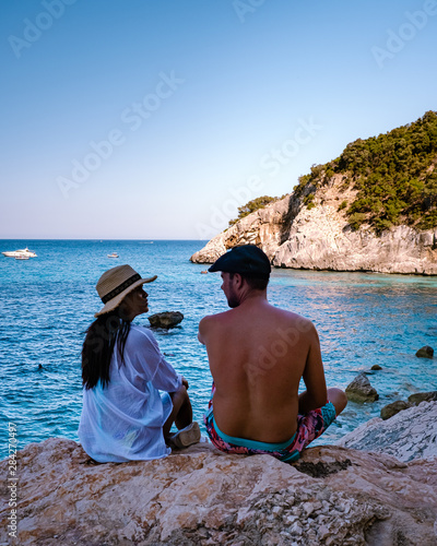 The beautiful bay in the Gulf of Orosei, Sardinia , couple during evening golden hour on the beach of Sardinia, men and woman on vacation in Italy  photo