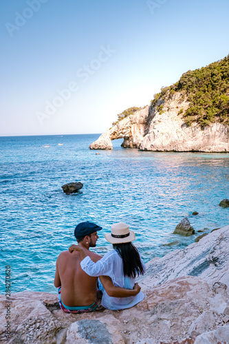 The beautiful bay in the Gulf of Orosei, Sardinia , couple during evening golden hour on the beach of Sardinia, men and woman on vacation in Italy  photo