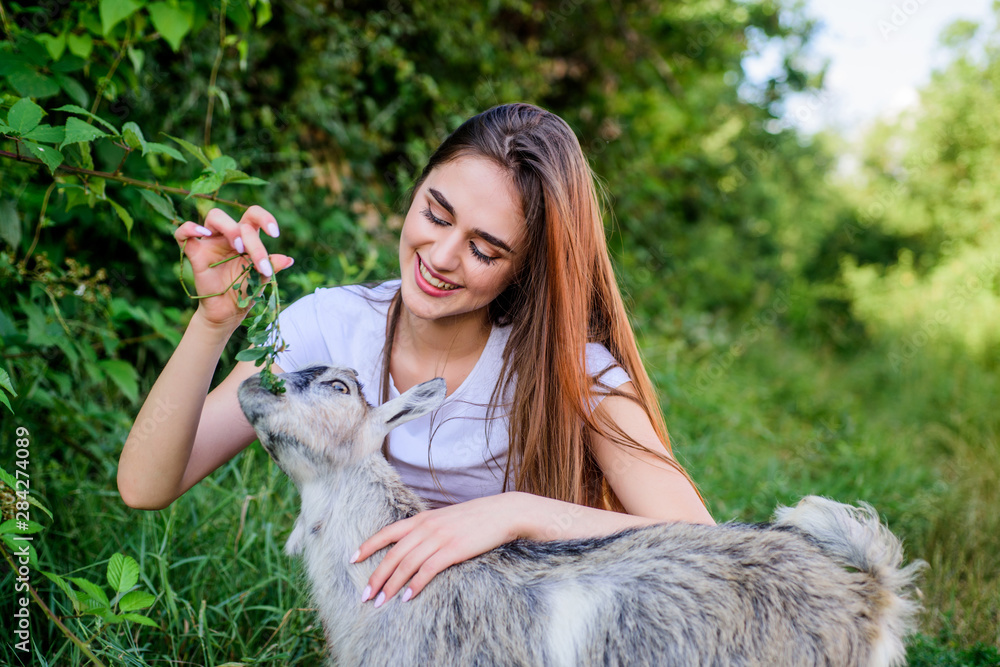 Woman and small goat green grass. Veterinarian occupation. Eco farm. Love and care. Animals law. Farm and farming concept. Village animals. Girl play cute goat. Feeding animal. Protect animals Woman and small goat green grass. Veterinarian occupation. Eco farm. Love and care. Animals law. Farm and farming concept. Village animals. Girl play cute goat. Feeding animal. Protect animals