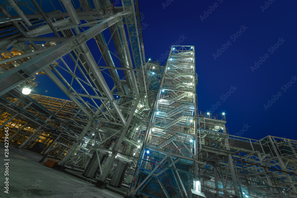 the form of metal pipes of a refinery in the open air at night