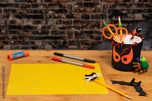 Halloween Crafting with a spooky pencil cup and a blank sheet of yellow construction paper ready to be used. There is plenty of Negative Space for copywriting.