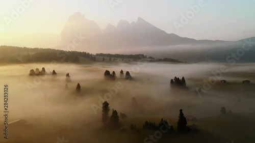 Sunrise drone aerial video in the Dolomites mountains. It was taken at Seiser Alm plateau on an amazing mystic morning with perfect foggy conditions. photo