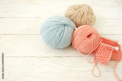 Knitting wool and knitting needles in pastel blue and pink colors on white wooden background. top view.copy space