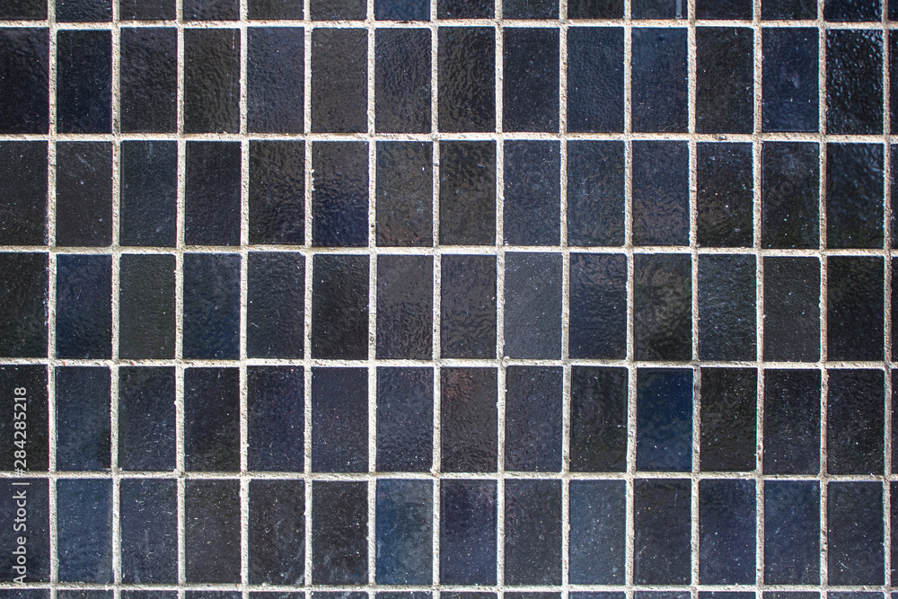 wall with black dark blue rectangular ceramic tiles with light cement. rough surface texture wall with black dark blue rectangular ceramic tiles with light cement. rough surface texture