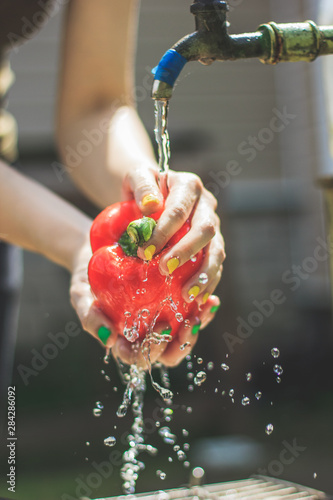 woman's hands wash red paprika. Paprika under flow of water. Ingredient for vegetarian salad. Vegetables that taste good.
