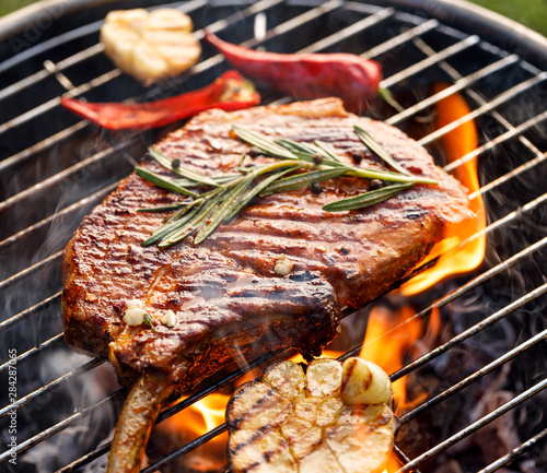 Obraz na płótnie Grilled bone-in pork chop, pork steak, tomahawk in spicy marinade on e a grill plate, close-up