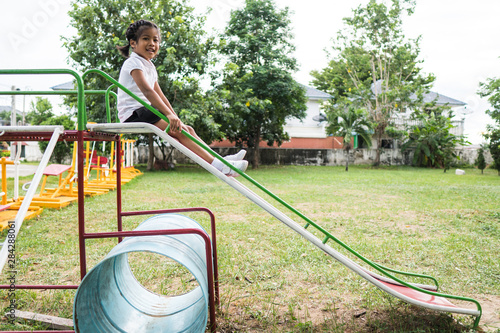 Healthy little kids are playing in the backyard, happy with the swings, rocking horses, slide carriages.