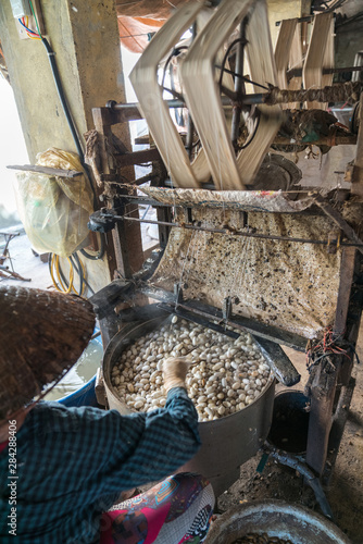Fototapeta Naklejka Na Ścianę i Meble -  Silkworm cocoon is boilling and unwinding by Vietnamese worman to make silk thread at village in Nam Dinh province, Vietnam