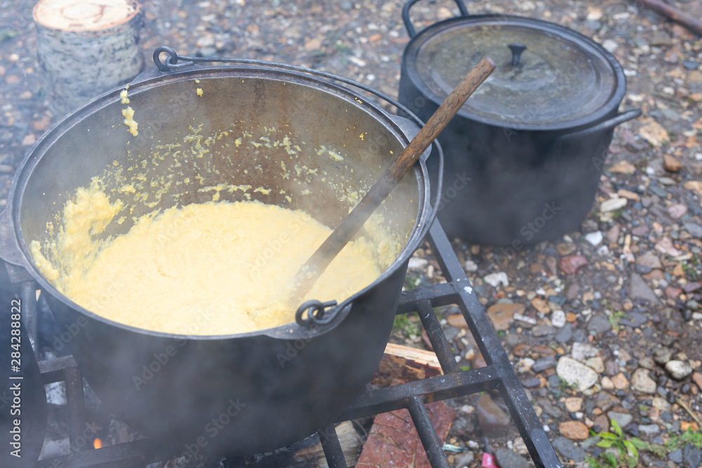 Corn porridge is cooked in a pot at the stake. camping kitchen. .traveling kitchen Corn porridge is cooked in a pot at the stake. camping kitchen. .traveling kitchen
