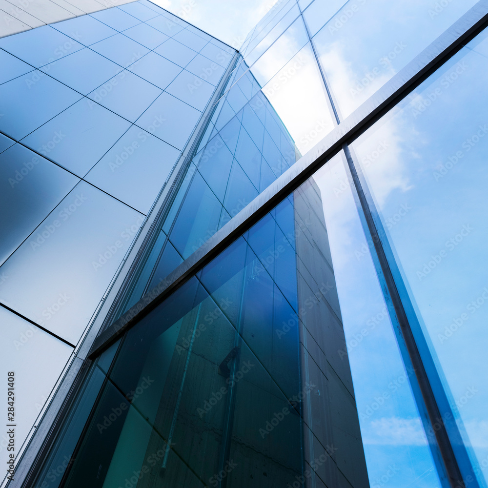 Obraz premium detail of modern office building with glass and steel reflecting blue sky
