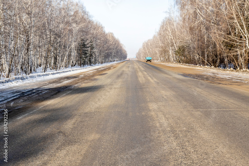 Road asphalt to the sky through the forest, winter landscape.