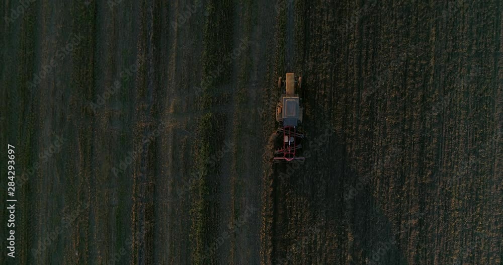 Aerial top view following the old yellow tractor plowing the field Aerial top view following the old yellow tractor plowing the field
