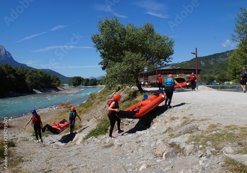 group of people carring biplace canoe out of the Durance river in french alps, France