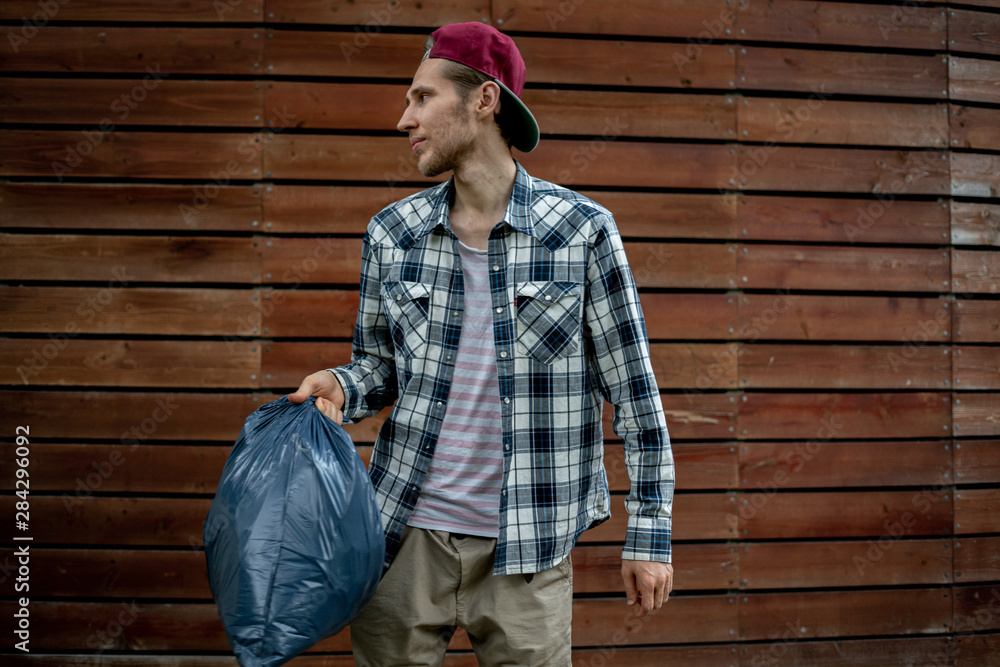 young man taking a trash bag with garbage away