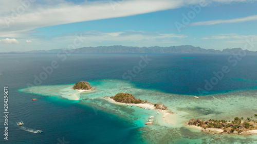aerial seascape island with white beach. Bulog Dos, Philippines, Palawan. tourist boats on coast tropical island. Seascape bay with turquoise water and coral reef.