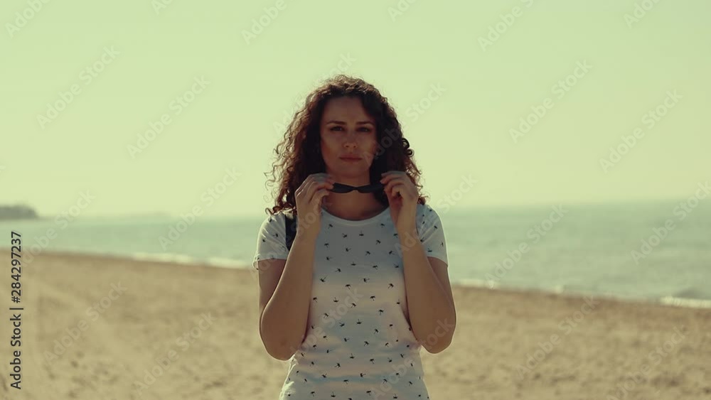 Close up of beautiful and young woman taking of sunglasses on the beach in slow motion Close up of beautiful and young woman taking of sunglasses on the beach in slow motion