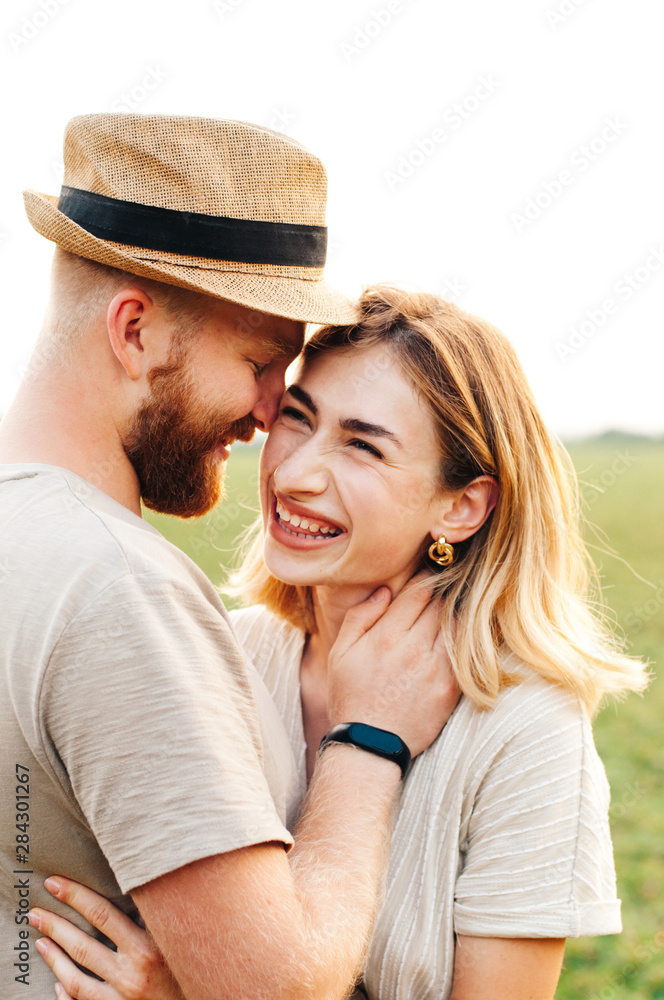 Handsome guy and blonde girl walking on the field on a warm sunset. gently hug, standing in the sun Handsome guy and blonde girl walking on the field on a warm sunset. gently hug, standing in the sun