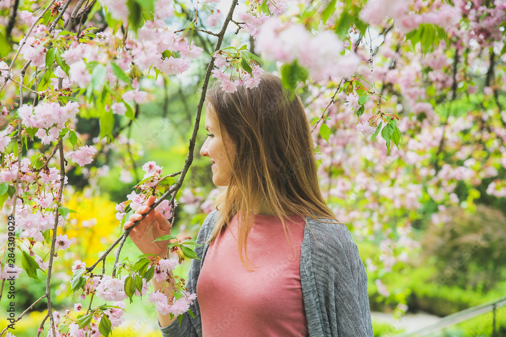Beautiful girl near blooming tree. Blossom sakura outdoors. Spring mood. Woman relaxing. Beautiful girl near blooming tree. Blossom sakura outdoors. Spring mood. Woman relaxing.