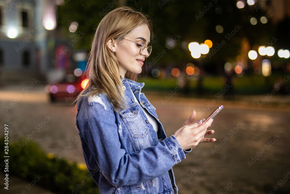 Young woman use mobile phone in city at night