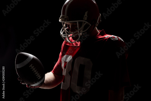 American football player with helmat looking at rugby ball photo