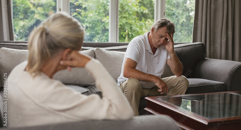 Active senior man with hand on forehead sitting on sofa in a comfortable home Active senior man with hand on forehead sitting on sofa in a comfortable home