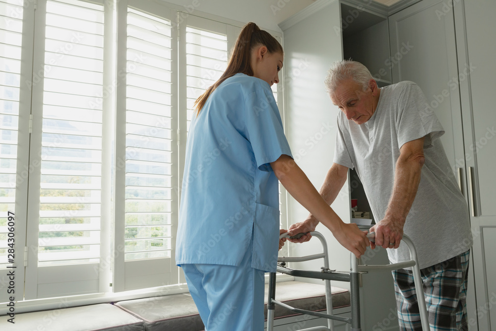 Fototapeta premium Female doctor helping active senior man to walk with walker