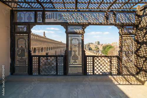 Passage surrounding the Mosque of Ibn Tulun framed by wooden window, Mashrabiya, Cairo, Egypt photo
