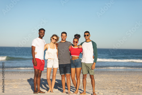 Group of happy friends standing together on the beach