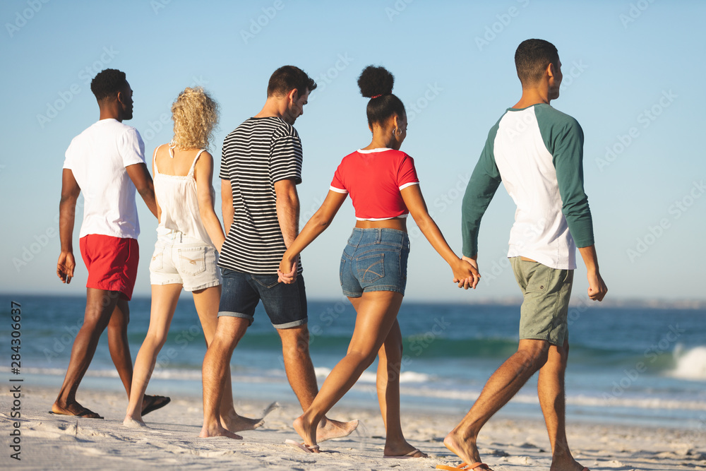 Obraz premium Group of friends walking together hand in hand on the beach